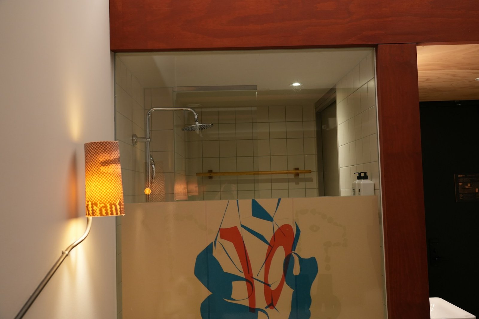 Banheiro contemporâneo com divisória de vidro fosco e iluminação acolhedora