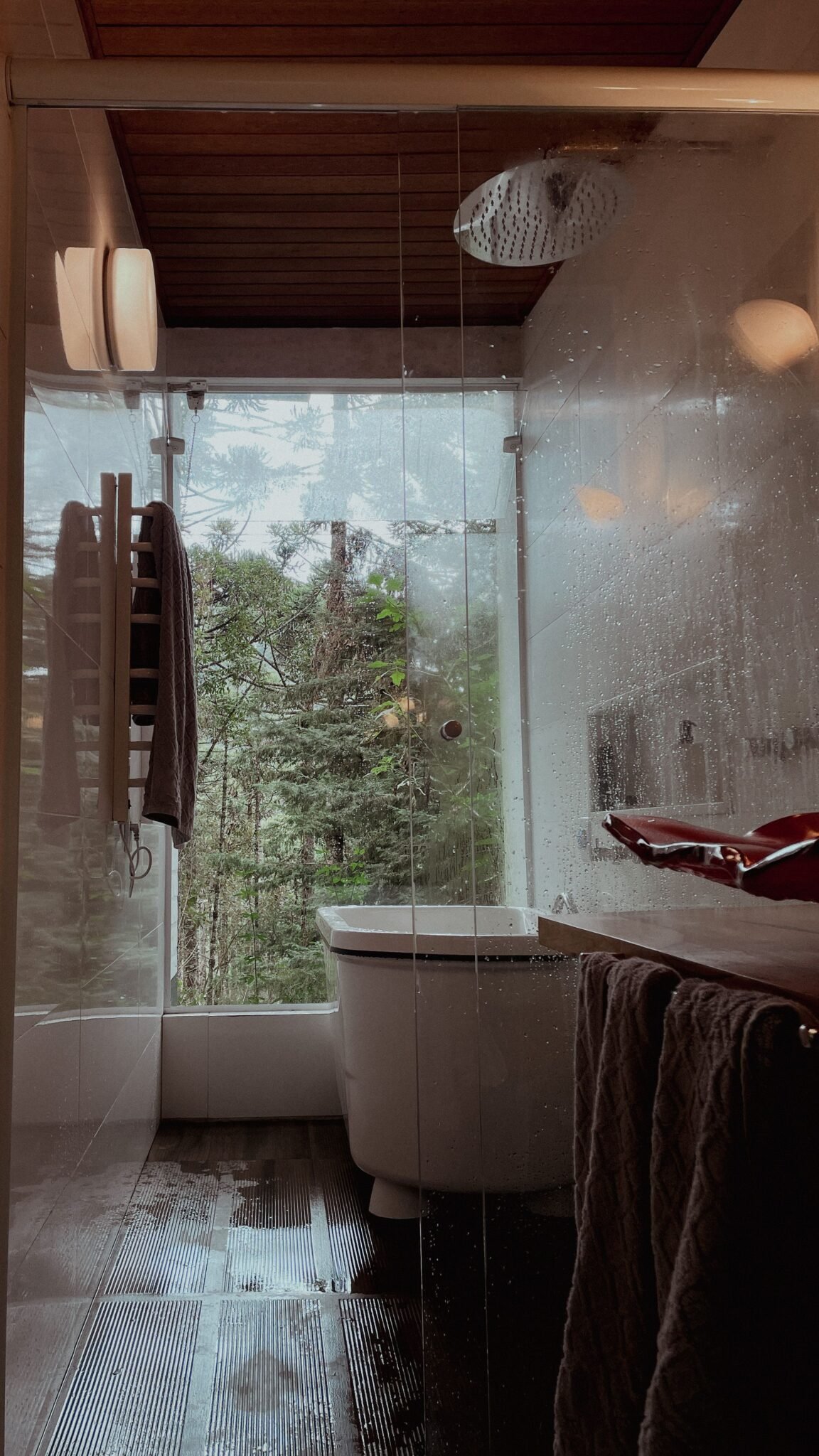 Banheiro contemporâneo com box de vidro e vista para árvores